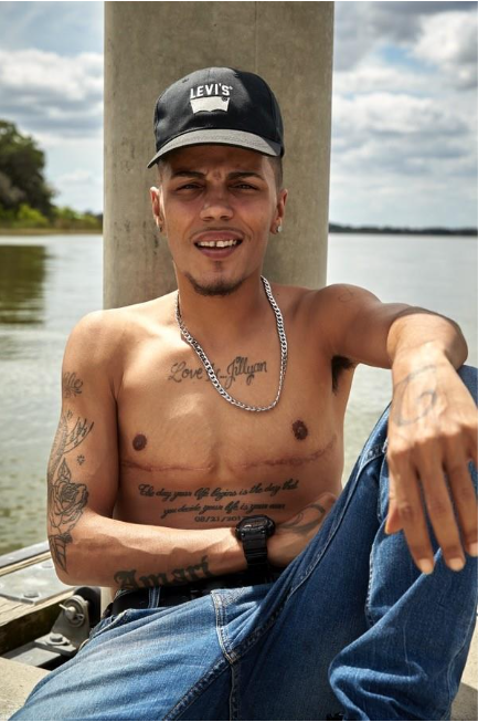 shirtless person sits facing the camera